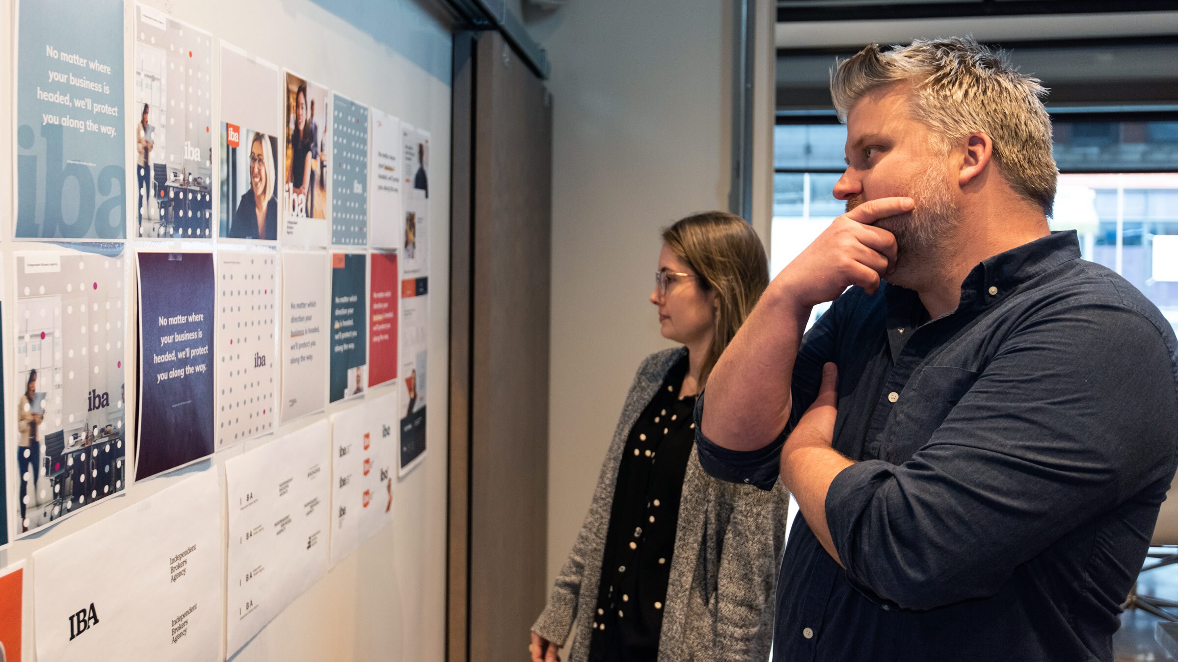 Designers at Atomicdust discuss branding concepts on a whiteboard.
