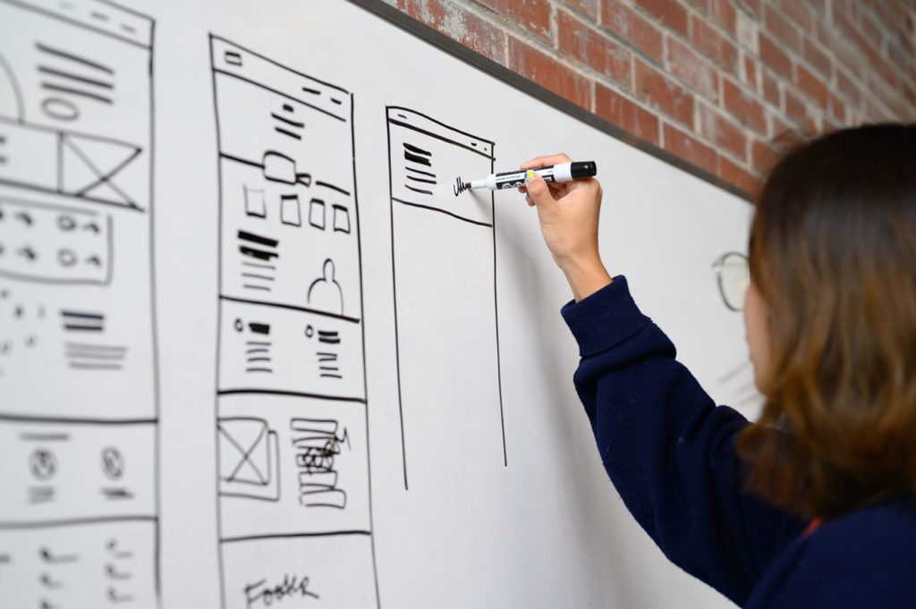 Designer mapping out landing page on whiteboard