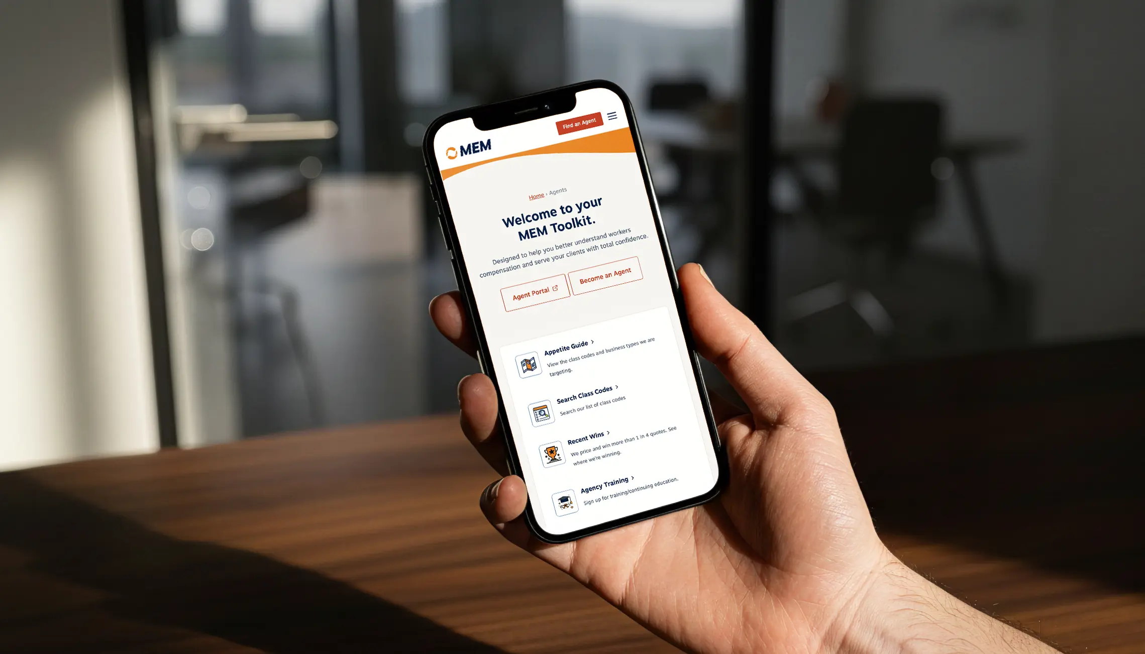 A person holds a cell phone with the MEM mobile website design on the screen